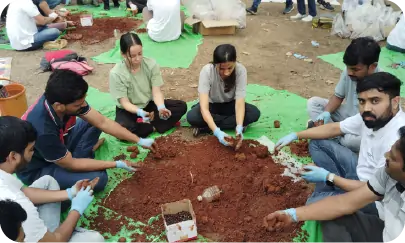 Volunteers working together to prepare seedballs on ground mats 